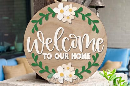Digital SVG file of a round Welcome to Our Home door hanger design with floral accents and layered lettering. This is an instant download laser cut design intended for DIY porch décor, entryway signs, and home décor projects. The digital file allows you to cut, paint, and assemble your own round door hanger using a laser machine. No physical sign is included—this flexible SVG digital file is ideal for seasonal or everyday welcome signs.