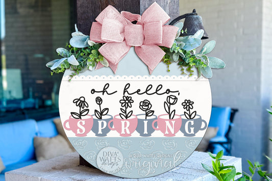 Digital SVG file of a round spring door hanger design featuring vintage teacups with floral stems and the phrase “oh hello spring.” This is an instant download laser cut design intended for DIY sign making. The digital file allows makers to create their own round door hanger, porch décor, or seasonal wall sign using a laser machine. SVG, DXF, PNG, EPS, JPG, PDF, and AI formats included. Ideal for cottagecore décor, floral spring signs, and romantic farmhouse style projects.