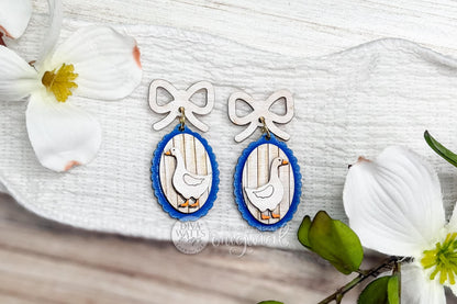 Digital SVG file for laser cut earrings featuring a cottagecore goose design with a bow topper and oval frame. This is a laser earring SVG only and an instant download, not a vinyl file. The digital design allows makers to create their own wood or acrylic earrings using a laser cutter. Ideal for cottagecore, grandma core, and coquette-style jewelry collections, spring accessories, and handmade gift earrings.