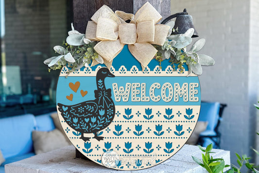 Round Door Hanger SVG Featuring A Faux Cross Stitch Goose Welcome Design With Grandmillennial Folk Art Style For Cottagecore Front Porch Decor And Cozy Entryway Signs, Includes Laser SVG And Vinyl SVG Files For Creating Layered Laser Cut Decor With A Nostalgic Handmade Feel